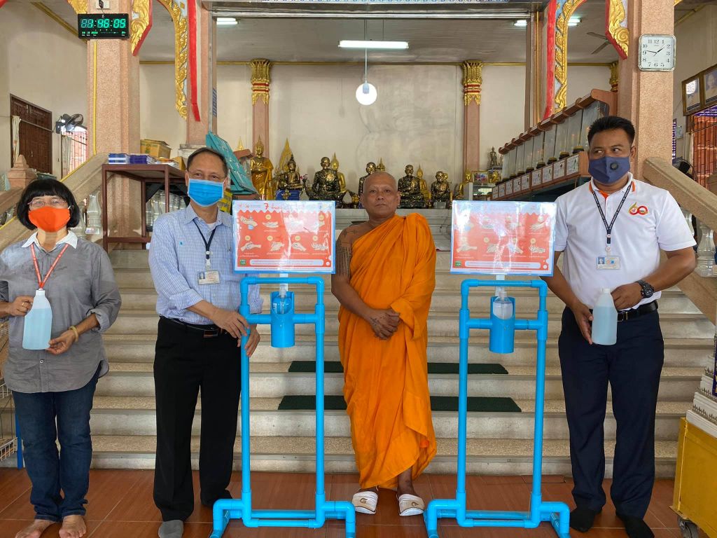 KMUTT volunteer student give a foot pedal alcohol disperser to the community around…