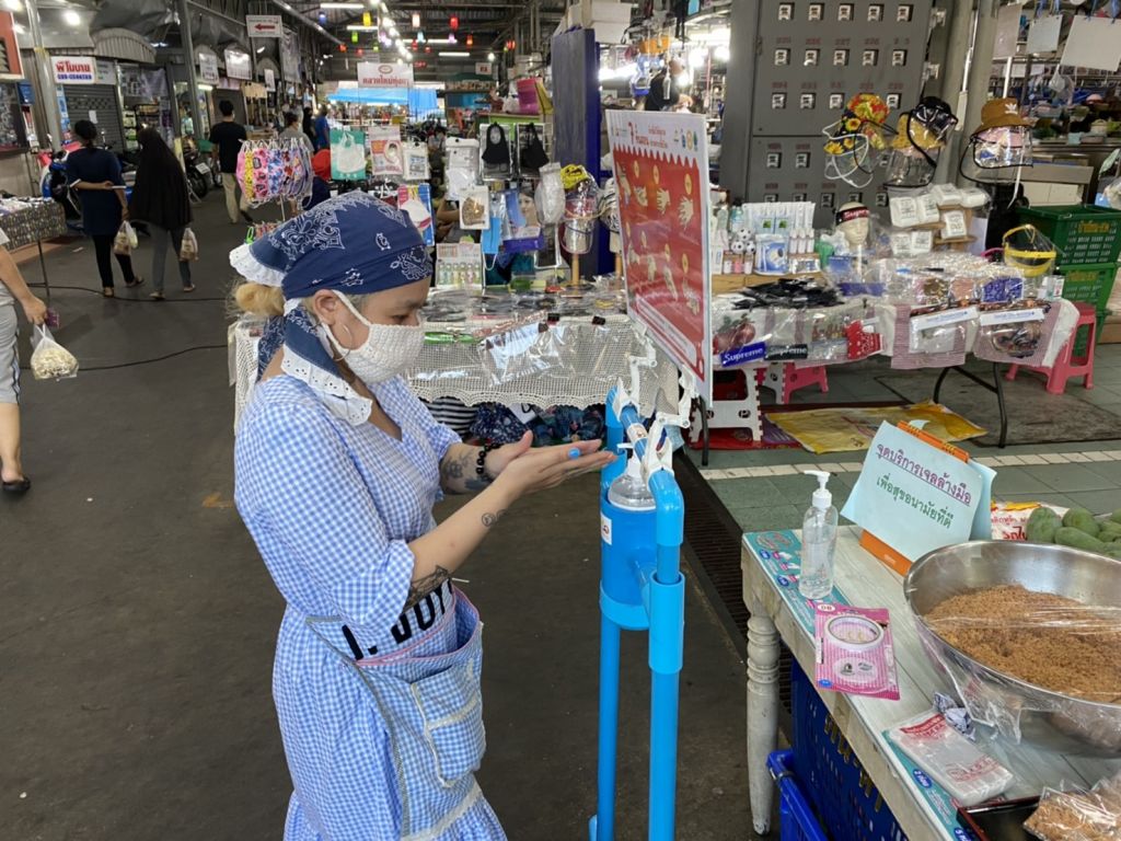 KMUTT volunteer student give a foot pedal alcohol disperser to the community around…