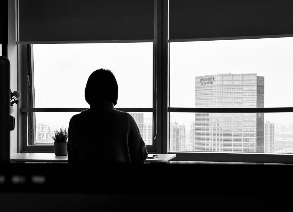 a person sitting in front of a window looking out